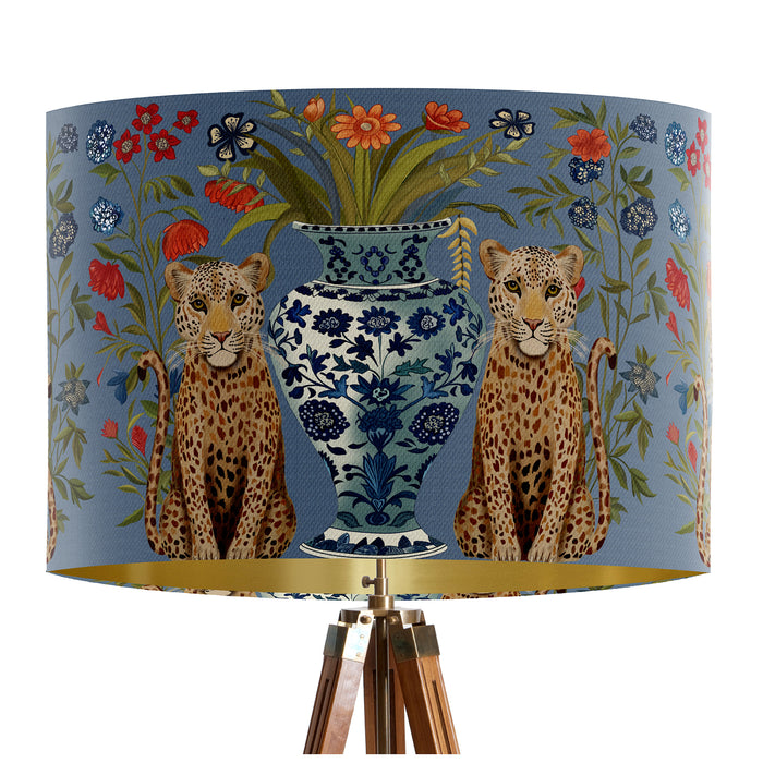 A maximalist design of leopards, chinoiserie vases and colourful flowers on a blue backdrop on a classic sized 30x21cm handcrafted fabric lampshade by artist Kelly Stevens-McLaughlan