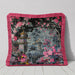 Black velvet cushion with pink fringe and a pagoda surrounded by pink and magenta flowers