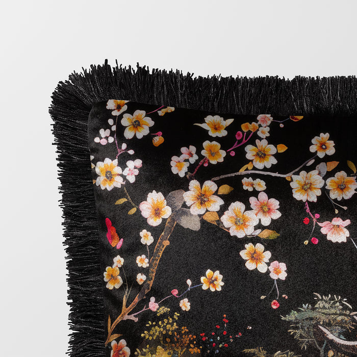 Black cushion with fringed edge, featuring a pagoda and lush floral accents.