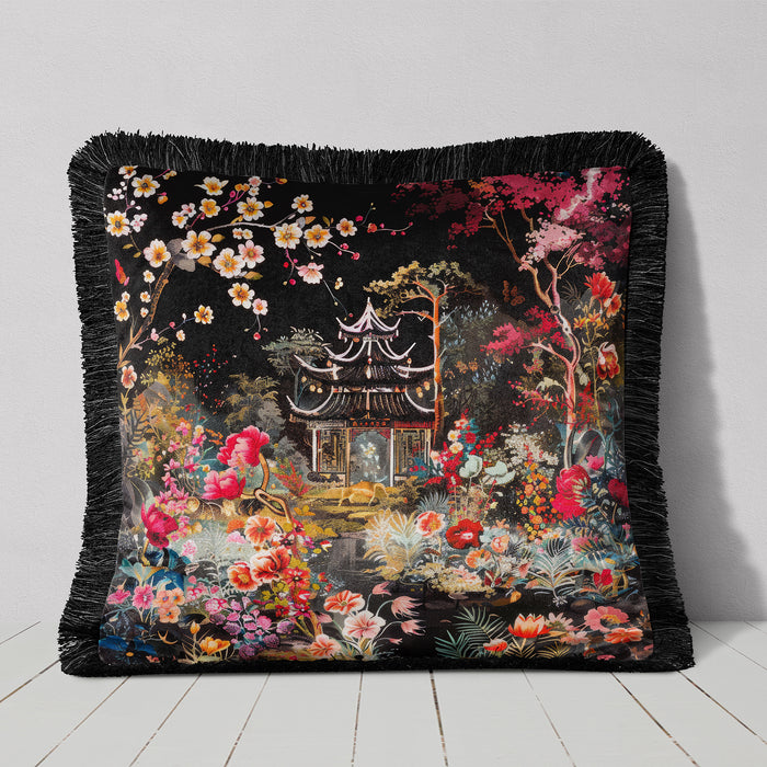 Black cushion with fringed edge, featuring a pagoda and lush floral accents.