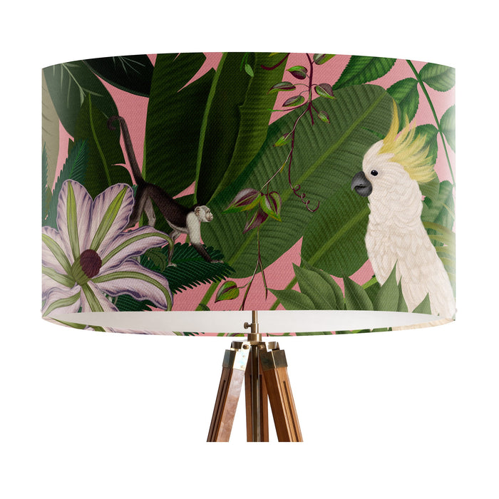 Parrots in white, green & blue along with monkeys sit amoungst green tropical leaves on a pink background on a large sized 40x25cm handcrafted fabric lampshade by artist Kelly Stevens-McLaughlan