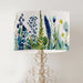 A stylish floral and grass design in harmonious shades of blue and green on a pristine white background on a classic sized 30x21cm handcrafted fabric lampshade by artist Kelly Stevens-McLaughlan