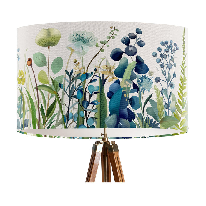 A stylish floral and grass design in harmonious shades of blue and green on a pristine white background on a large sized 40x25cm handcrafted fabric lampshade by artist Kelly Stevens-McLaughlan