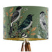 Intricately drawn birds, sit on branches and leaves with a green backdrop on a classic sized 30x21cm handcrafted fabric lampshade by artist Kelly Stevens-McLaughlan