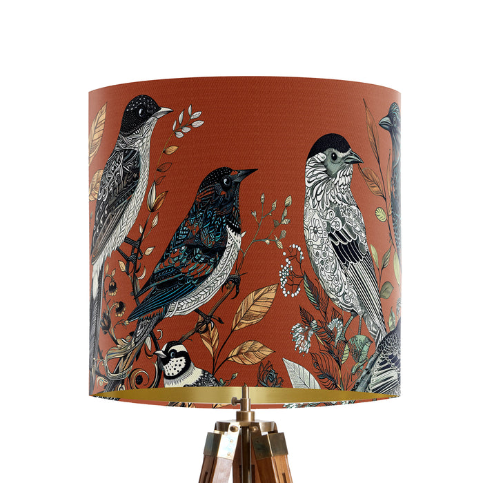 Intricately drawn birds, sit on branches and leaves with a rust orange backdrop on a small sized 20x18cm handcrafted fabric lampshade by artist Kelly Stevens-McLaughlan