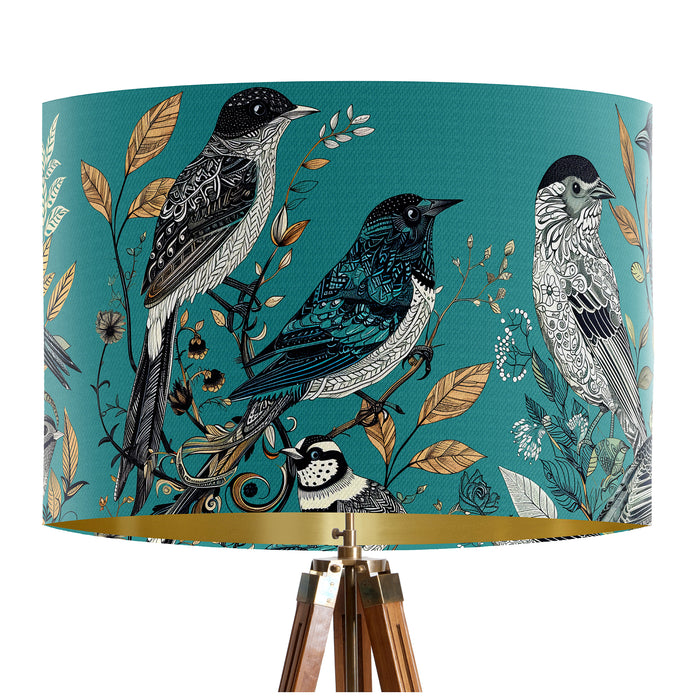 Intricately drawn birds, sit on branches and leaves with a blue backdrop on a classic sized 30x21cm handcrafted fabric lampshade by artist Kelly Stevens-McLaughlan