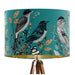 Intricately drawn birds, sit on branches and leaves with a blue backdrop on a classic sized 30x21cm handcrafted fabric lampshade by artist Kelly Stevens-McLaughlan